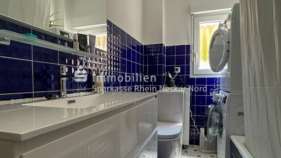Badezimmer mit blau gefliester Wand und Fenster